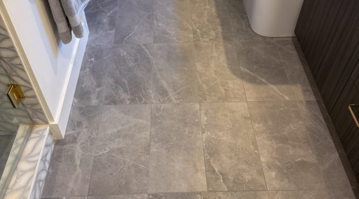A bathroom floor covered in large-format gray marble tiles, creating a sleek and modern look.