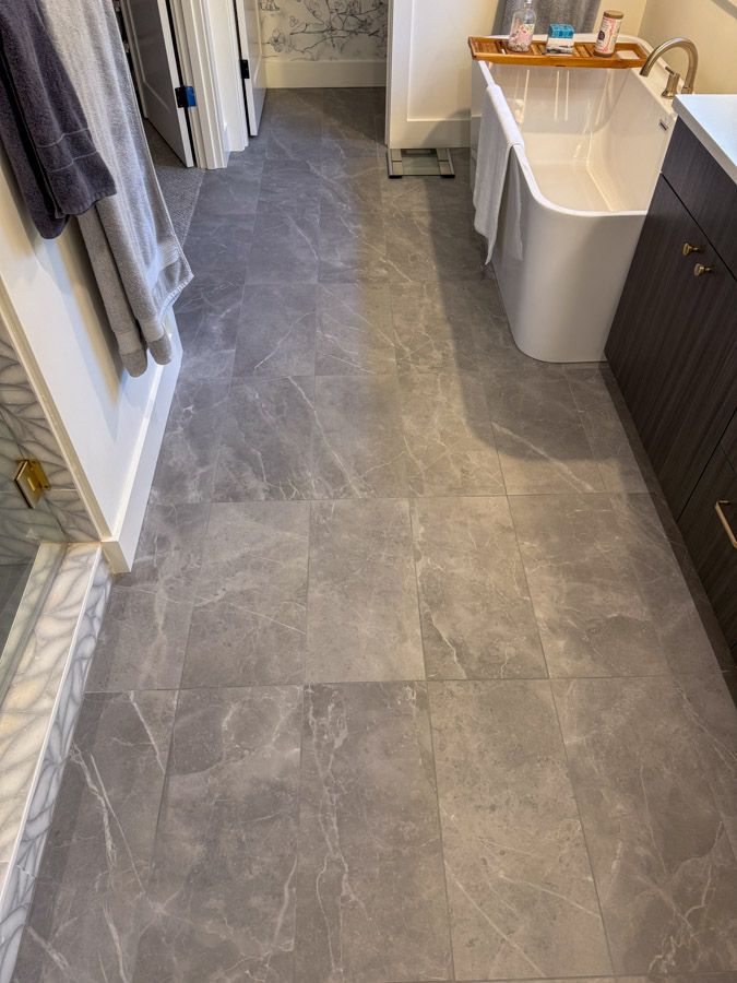 A bathroom floor covered in large-format gray marble tiles, creating a sleek and modern look.