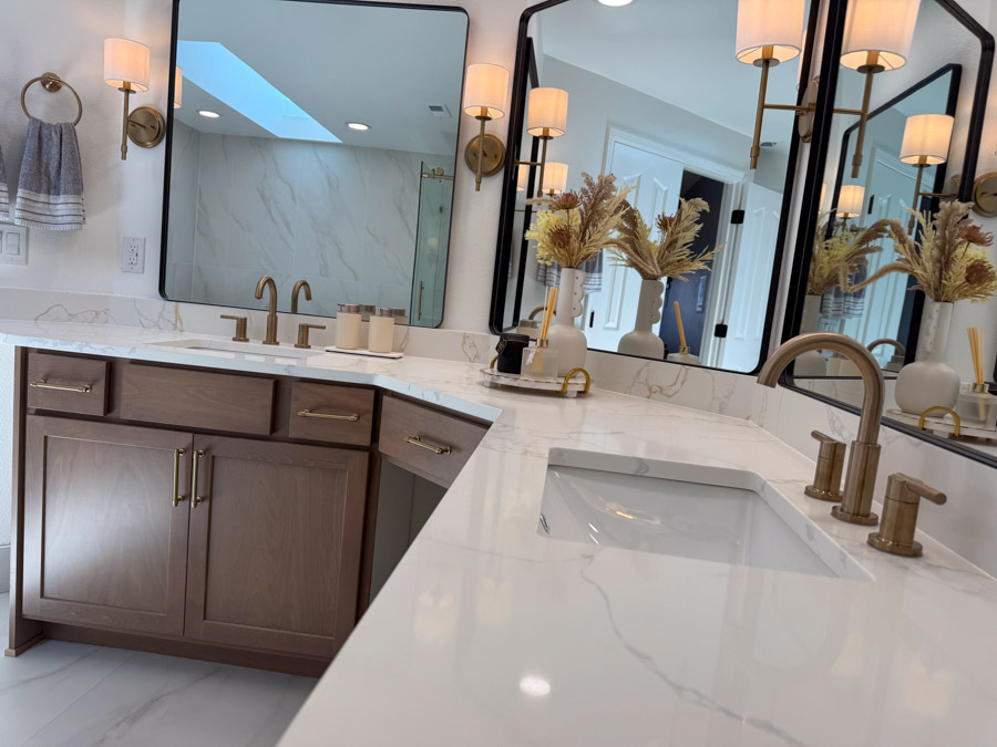 A luxurious double vanity with white marble countertops, brass hardware, and decorative wall sconces.