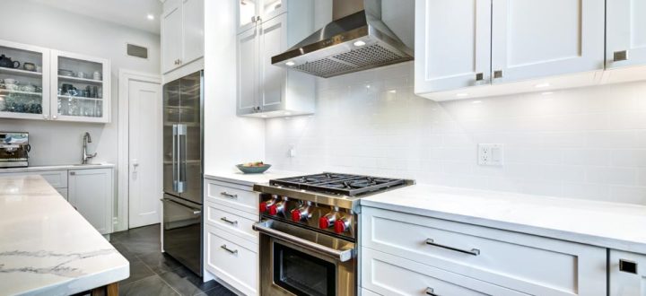 A contemporary kitchen featuring white cabinetry, marble countertops, and sleek, dark tile flooring providing a modern look.