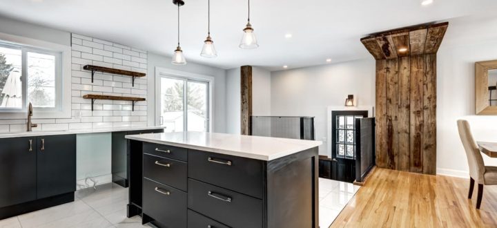 A rustic-modern kitchen blending traditional wooden elements with modern black cabinetry and a white tile backsplash, highlighted by unique pendant lighting.