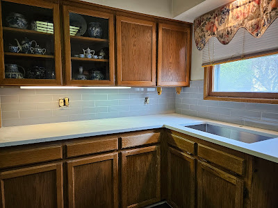 Traditional kitchen featuring classic wooden cabinetry and a light teal subway tile backsplash, creating a warm and inviting atmosphere.