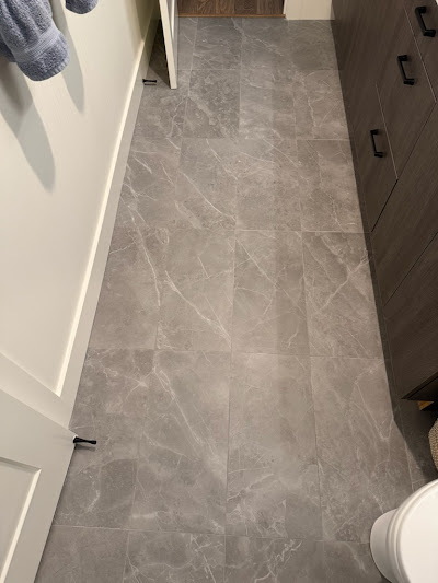 Luxurious marble floor tile installation in a bathroom, featuring large tiles with subtle grey veining, enhancing the room's modern aesthetic.