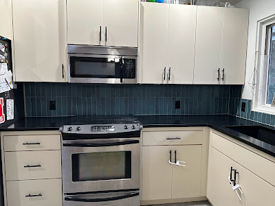 Spacious kitchen with stainless steel appliances and a deep teal subway tile backsplash, adding a modern and elegant touch to the light-colored cabinetry.