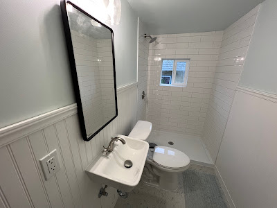 Small, efficiently designed bathroom with white subway tiles on the walls, wood paneling, and a compact sink and toilet setup, maximizing space in a stylish way.